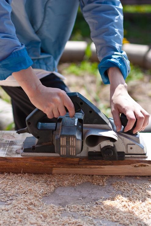 Anwendung eines Elektrohobels - Seitenansicht Mann mit Elektrohobel Seitenansicht Hochformat